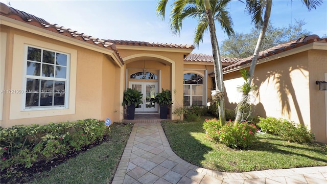 entrance to property featuring a lawn and french doors