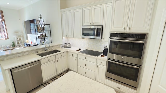 kitchen featuring sink, appliances with stainless steel finishes, kitchen peninsula, decorative backsplash, and white cabinets