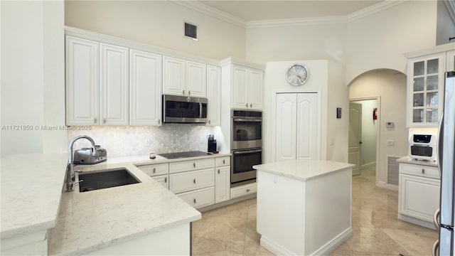 kitchen featuring appliances with stainless steel finishes, white cabinetry, sink, decorative backsplash, and light stone counters