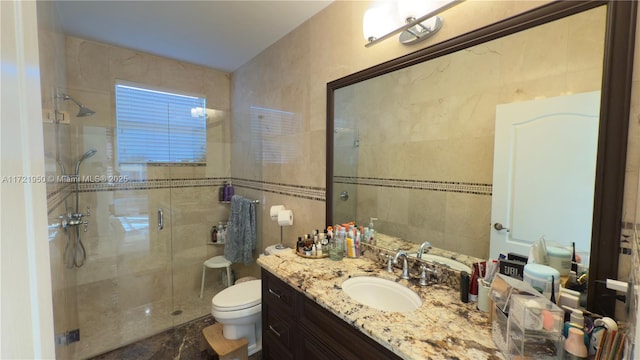 bathroom featuring vanity, toilet, a shower with shower door, and tile walls