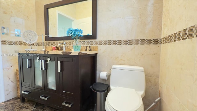 bathroom featuring vanity, toilet, and tile walls