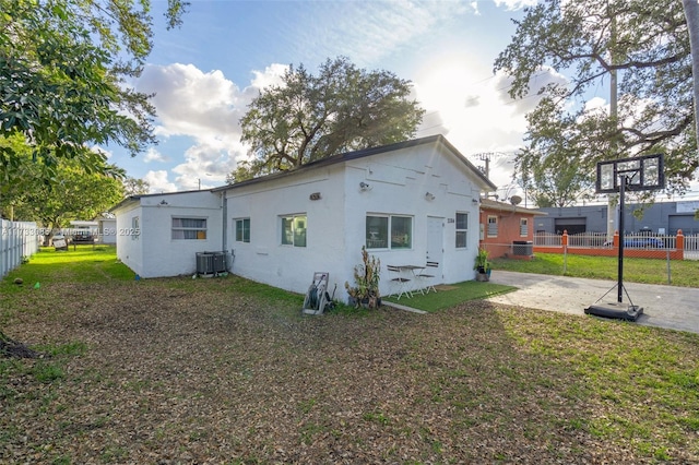 back of property with central AC, a patio, and a lawn