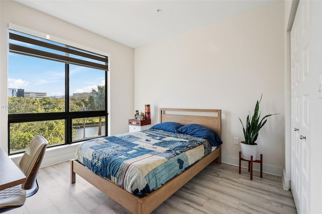 bedroom with hardwood / wood-style floors and a water view