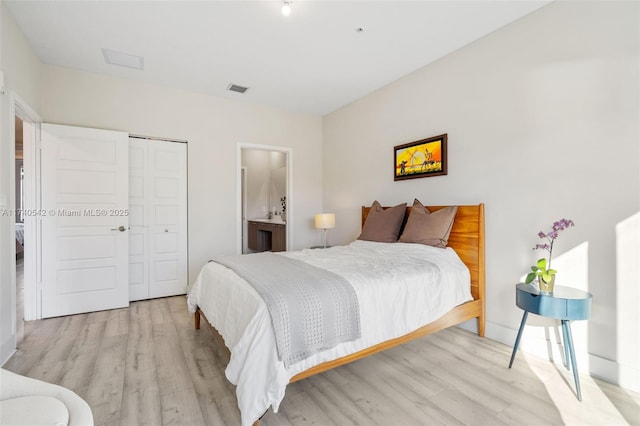 bedroom featuring ensuite bathroom, light wood-type flooring, and a closet