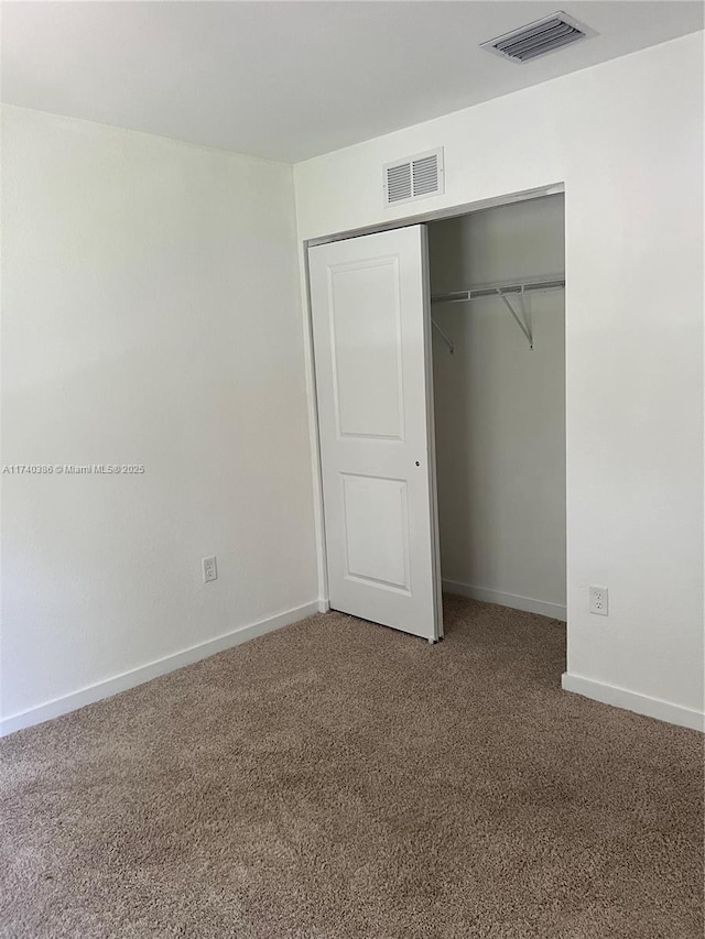 unfurnished bedroom featuring carpet flooring and a closet