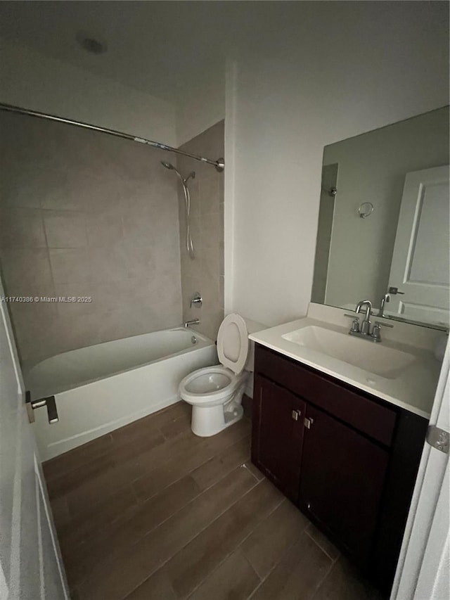 full bathroom featuring tiled shower / bath combo, wood-type flooring, vanity, and toilet