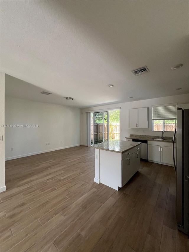 kitchen featuring a kitchen island, sink, stainless steel fridge, white cabinets, and hardwood / wood-style flooring