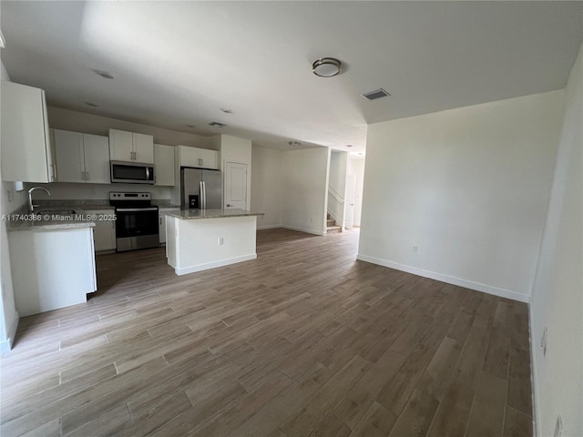 kitchen featuring sink, stainless steel appliances, a center island, white cabinets, and light wood-type flooring