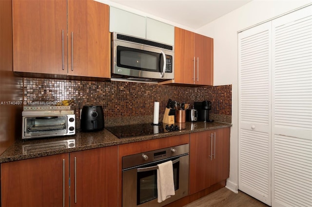 kitchen with dark stone countertops, decorative backsplash, dark hardwood / wood-style flooring, and stainless steel appliances