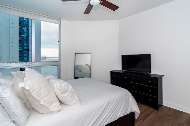 bedroom with expansive windows, dark wood-type flooring, and ceiling fan