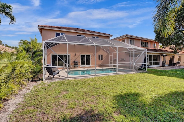 rear view of property featuring a yard, a patio area, and glass enclosure