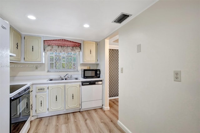 kitchen featuring white dishwasher, sink, range with electric cooktop, and light wood-type flooring