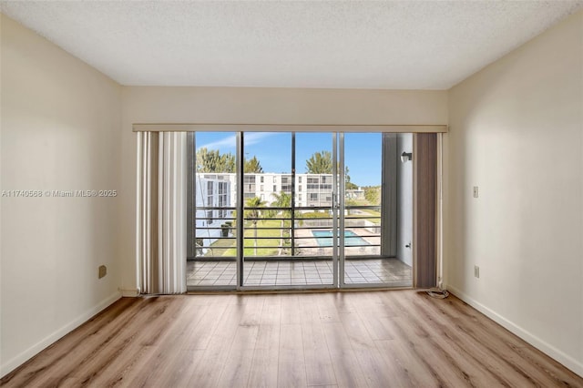 spare room featuring a textured ceiling and light wood-type flooring