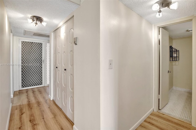 hallway featuring a textured ceiling and light hardwood / wood-style floors