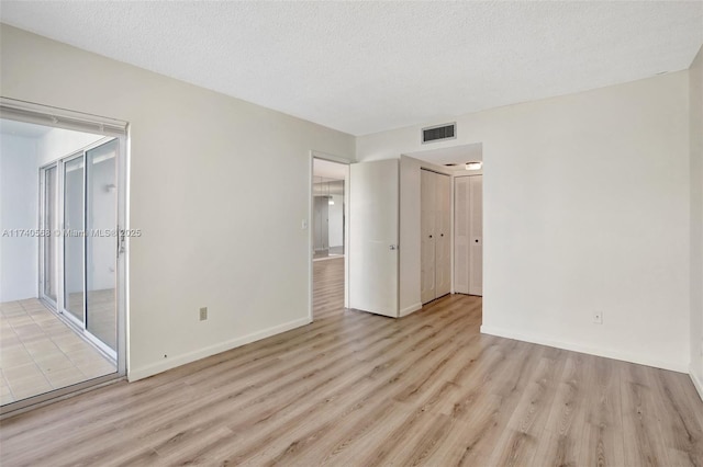 unfurnished bedroom with light hardwood / wood-style flooring and a textured ceiling