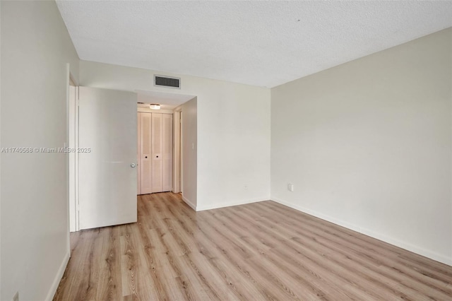 spare room with light hardwood / wood-style flooring and a textured ceiling