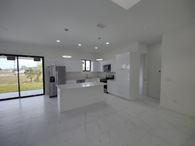 kitchen with sink, decorative light fixtures, appliances with stainless steel finishes, a kitchen island, and white cabinets