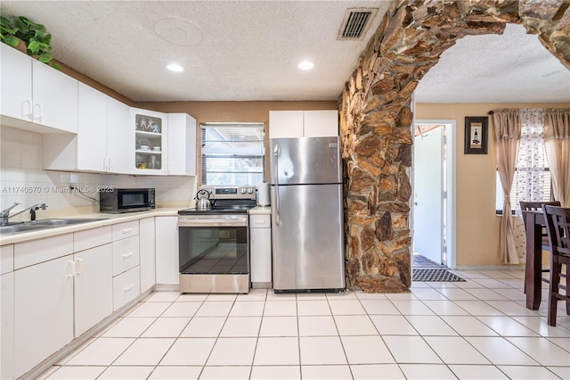 kitchen with sink, white cabinetry, stainless steel appliances, tasteful backsplash, and a wealth of natural light