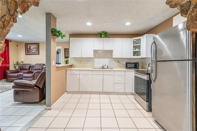 kitchen with sink, light tile patterned floors, stainless steel appliances, decorative backsplash, and white cabinets