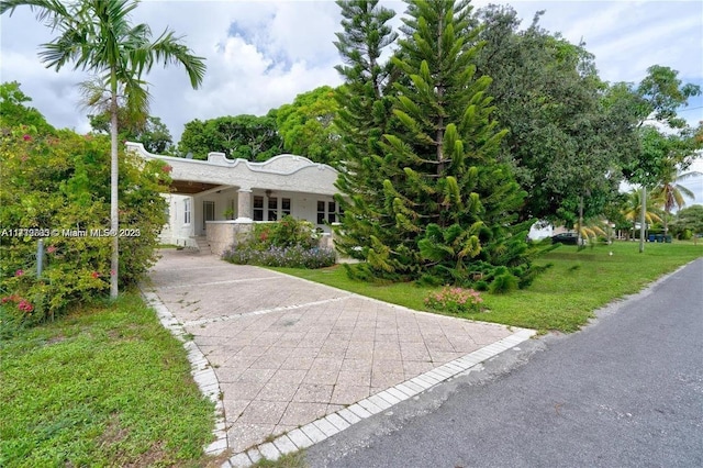 view of front facade with a carport, a front yard, and driveway