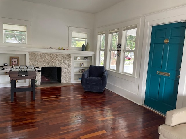 sitting room with a stone fireplace, dark wood finished floors, and baseboards