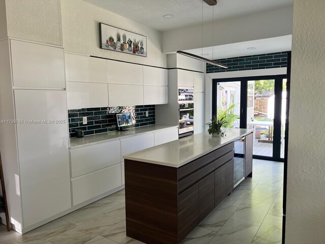 kitchen featuring dark brown cabinets, a center island, white cabinets, and decorative backsplash