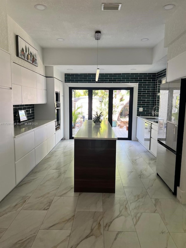 kitchen featuring pendant lighting, light countertops, white cabinets, a kitchen island, and modern cabinets