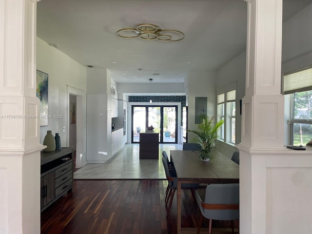 dining area with decorative columns, dark wood-type flooring, and a wealth of natural light