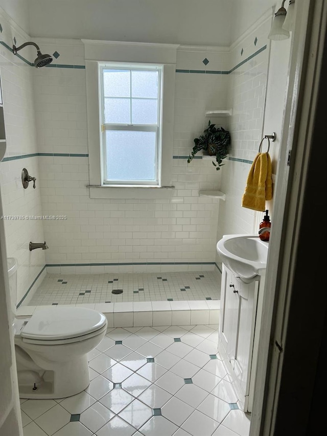 bathroom with a tile shower, vanity, tile patterned floors, and toilet