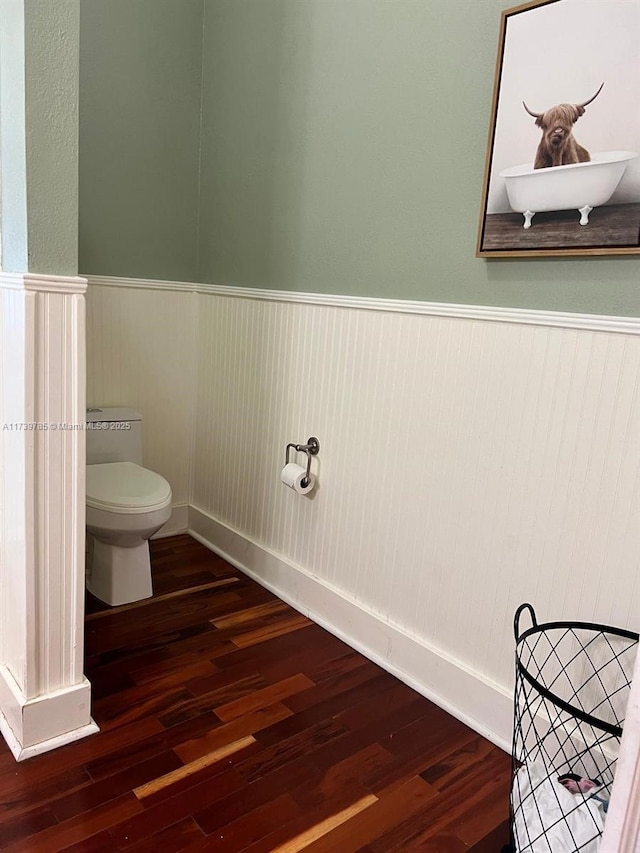 bathroom with a wainscoted wall, wood finished floors, and toilet