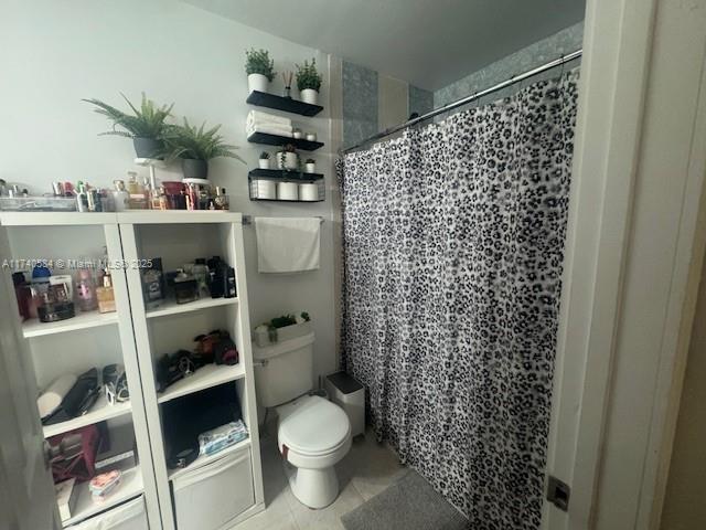 bathroom with tile patterned flooring, walk in shower, and toilet