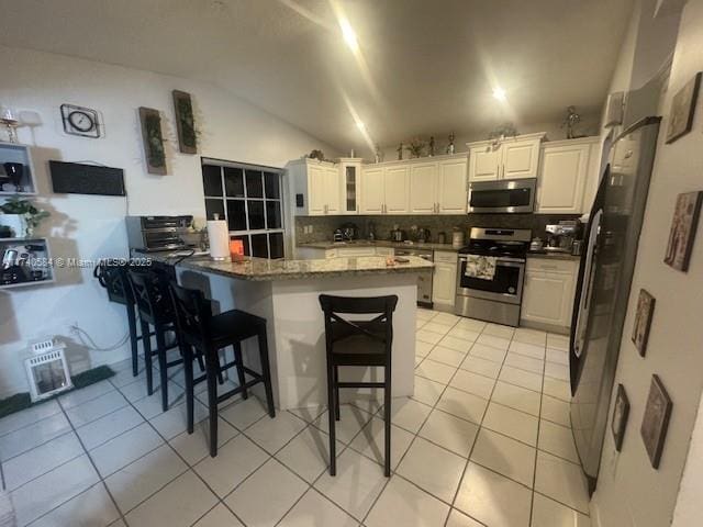 kitchen featuring light tile patterned flooring, white cabinetry, a kitchen breakfast bar, kitchen peninsula, and stainless steel appliances