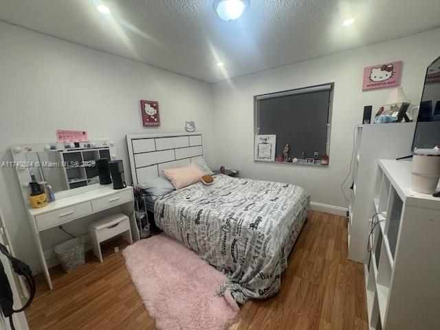 bedroom featuring hardwood / wood-style flooring and a textured ceiling