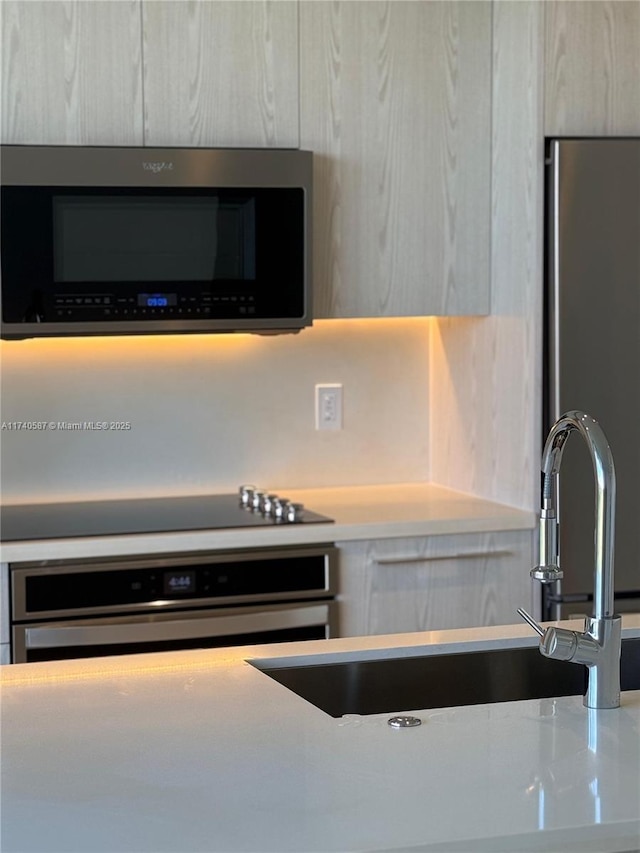 interior details featuring appliances with stainless steel finishes, sink, and light brown cabinets