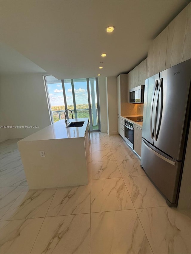 kitchen featuring a kitchen island with sink, sink, stainless steel appliances, and floor to ceiling windows