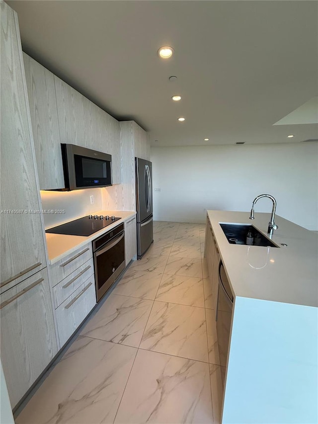 kitchen with sink, stainless steel appliances, an island with sink, and light brown cabinets