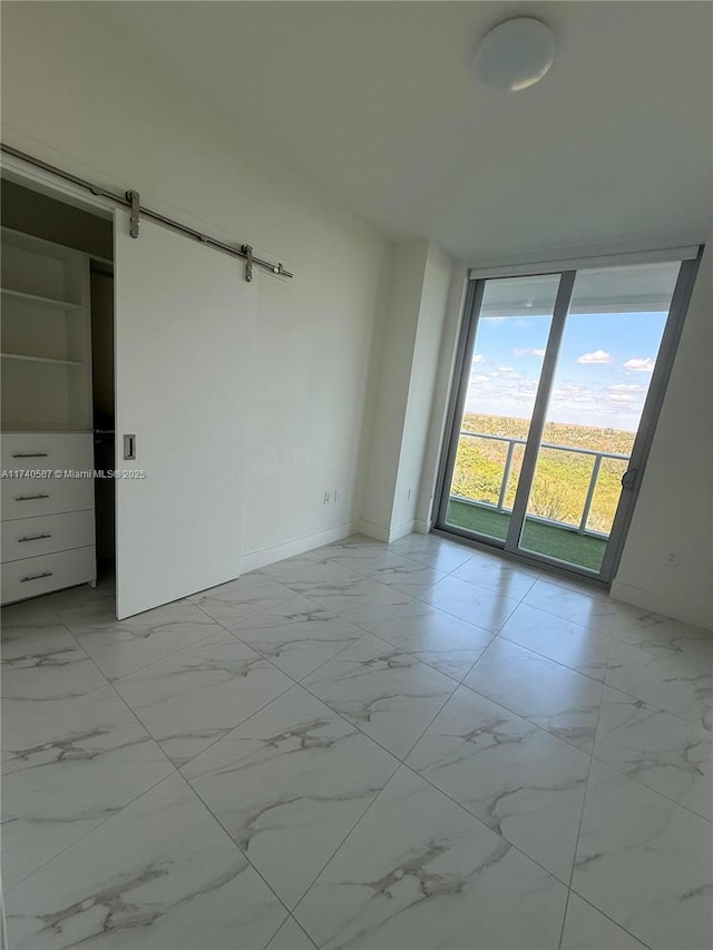 unfurnished room with floor to ceiling windows and a barn door