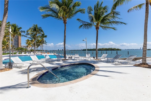 view of pool with a patio, a water view, and a community hot tub