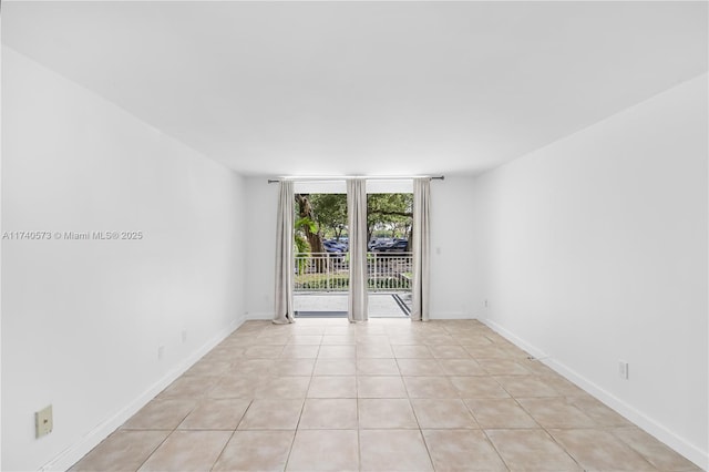 unfurnished room with light tile patterned flooring and a wall of windows