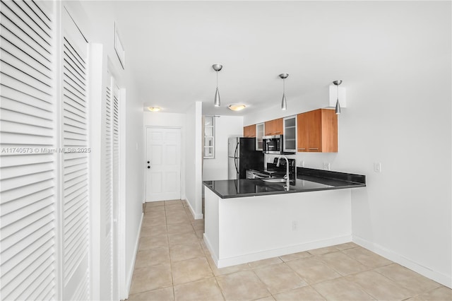 kitchen with pendant lighting, sink, light tile patterned floors, black refrigerator, and kitchen peninsula