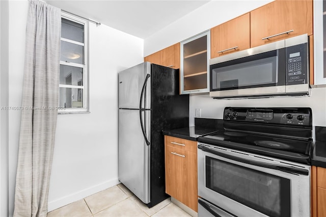 kitchen with stainless steel appliances, dark stone countertops, and light tile patterned floors