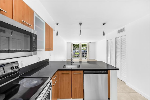 kitchen with light tile patterned flooring, appliances with stainless steel finishes, sink, and kitchen peninsula