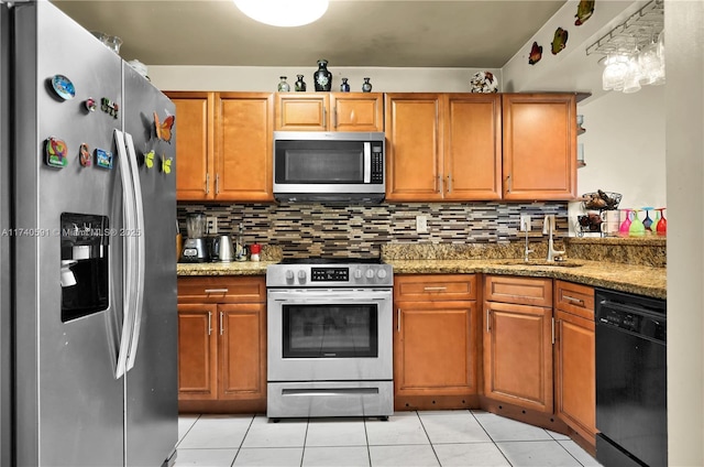 kitchen with light stone counters, stainless steel appliances, sink, and backsplash