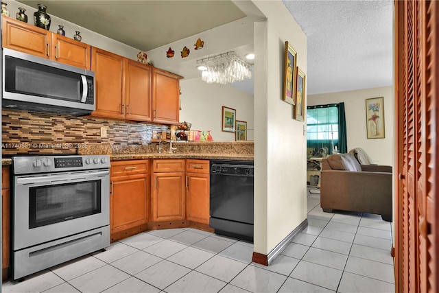 kitchen featuring sink, appliances with stainless steel finishes, light tile patterned flooring, decorative backsplash, and dark stone counters