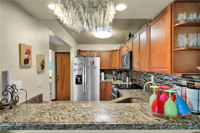 kitchen with appliances with stainless steel finishes, sink, light stone counters, and decorative backsplash