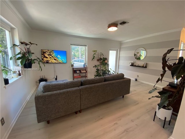 living area with ornamental molding, visible vents, light wood-style flooring, and baseboards