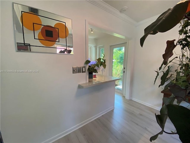 corridor featuring light wood finished floors, baseboards, and ornamental molding