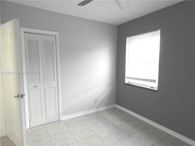 unfurnished bedroom with ceiling fan, a closet, and baseboards