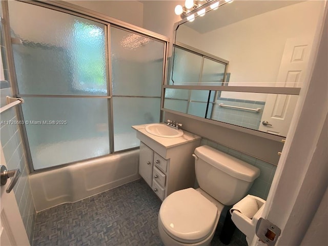 bathroom with toilet, combined bath / shower with glass door, and vanity