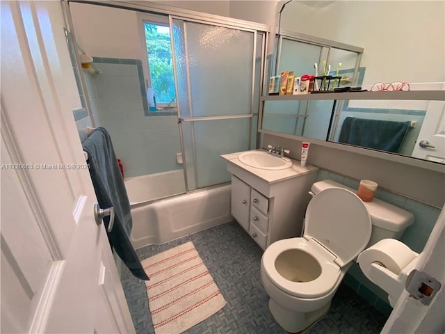 bathroom featuring enclosed tub / shower combo, vanity, and toilet